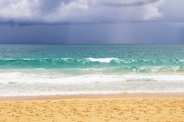 Sea waves, beach and rainy cloudy sky