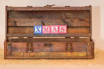 The word Christmas written with blue and red letter blocks in vintage wood chest