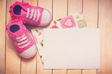 It`s a girl card. Top view of baby girl shoes and empty card next to it.