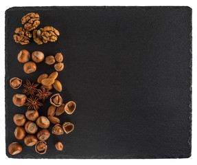 Nuts mix on a black slate board. Isolated on white background.