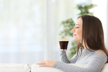 Woman smelling a cup of coffee at home