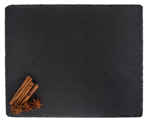 Cinnamon and star anise on a black slate board. Isolated on whit
