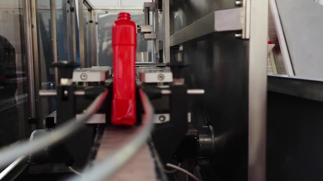Food processing plant: machine turns red plastic bottles in right direction prior to next stage in production - filling;