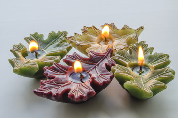 burning candles in the form of a leaf on a light background
