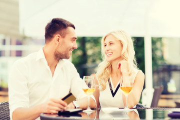 happy couple with bank card and bill at restaurant