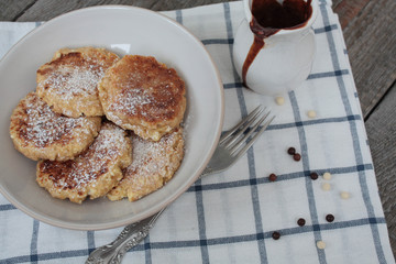 Russian cheese pancakes with chocolate and marshmallow on a light plate and wooden background. sweet delicious Russian food.