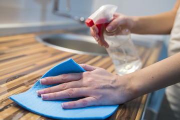 Adult female in gloves with rag and cleanser cleaning up