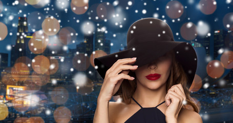 beautiful woman in black hat over night city