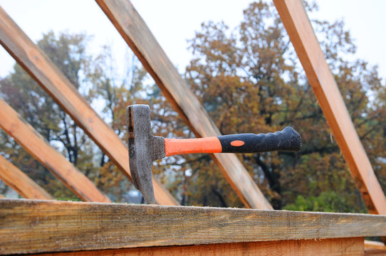 Hammer on wood. Hammer close-up on a background of a roof under construction. The builder has left the hammer in board