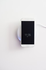 White smartphone charged by wireless charger
