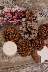 Fir branch in snow, cone, candle, christmas decoration on wooden background