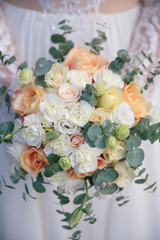 beautiful bouquet of different colors in the hands of the bride in a white dress