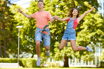 Naklejka na ściany i meble happy teenage couple jumping at summer park