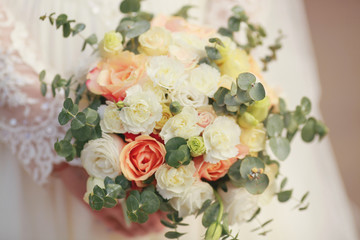 beautiful bouquet of different colors in the hands of the bride in a white dress