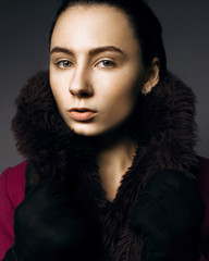 Serious portrait of a girl in a fur coat in the studio