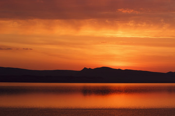 Fototapeta na wymiar Russia. Khakassia. Sunrise on the Lake Shire. On the horizon, the silhouette of hills and mountains.
