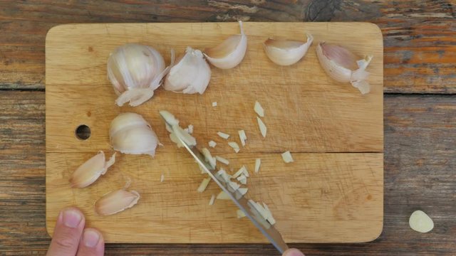 Chopping garlic on a rustic wooden table - flat lay 4K