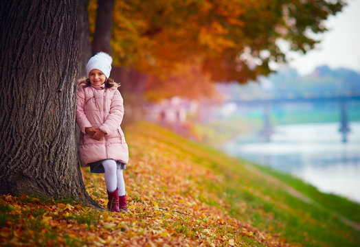 pretty girl walking in autumn park among fallen leaves