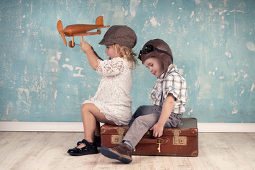 Urlaubskonzept, zwei kleine Kinder mit Koffer und Flieger