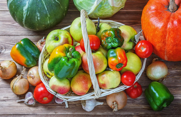 Apples, onions, garlic, tomatoes, cabbage and pumpkins on a wooden table.