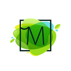 M letter logo in square frame at green watercolor splash backgro