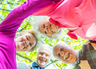 Four elder men and women looking down to camera outdoor. Happine