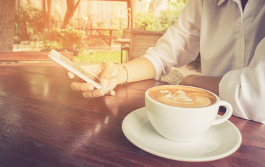 Woman use mobile phone with coffee cup vintage tone.