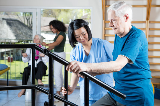 Senior citizens working out at gym with multi racial trainers he
