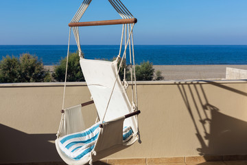 A swing chair on a balcony with sea view at sunset