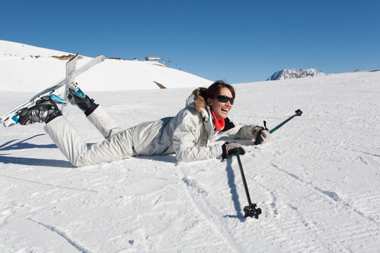 femme souriante avec des skis tomb&eacute;e par terre dans la neige