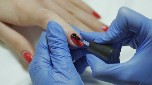 Manicurist gets a top coating on the nail