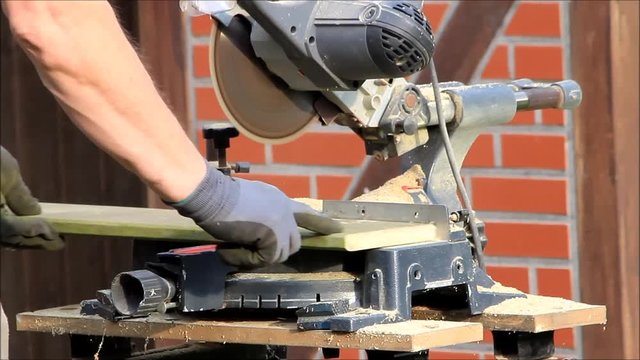 man using electric saw to cutting wood 
