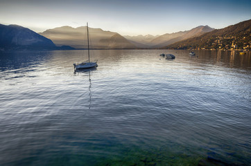 Fototapeta na wymiar Lake Maggiore, Italy. Sunset Panoramic view of Lake Maggiore with a boat in the water. Verbania, Piedmont.
