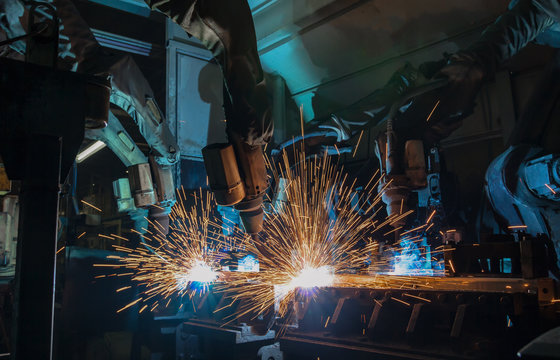 Industrial team robots welding in automotive part factory
