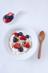 muesli with berries and yogurt on a white backgrund