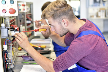 Two electrician students working at electrical panel