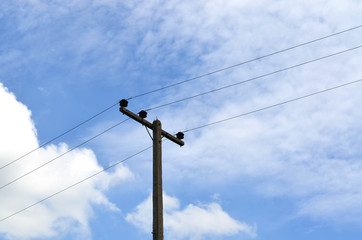 Electrical pole with power lines against hazy blue sky