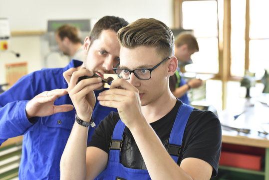 Instructor examining workpiece of trainee
