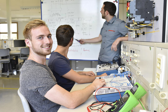 Portrait of smiling student with technical instructor at whiteboard