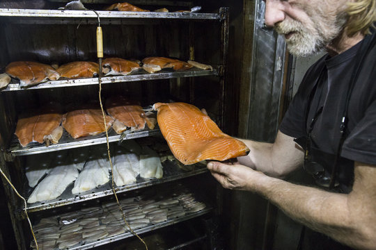 Man looking at freshly smoked salmon steak in a smokehouse
