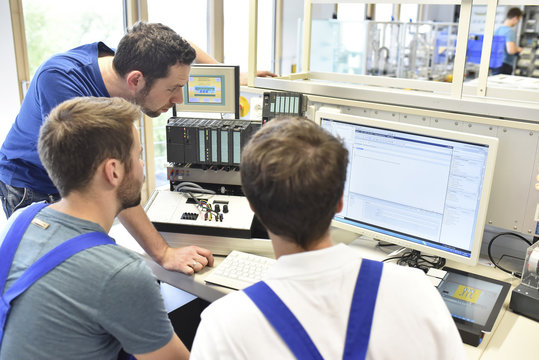 Technical instructor teaching students at computer screen