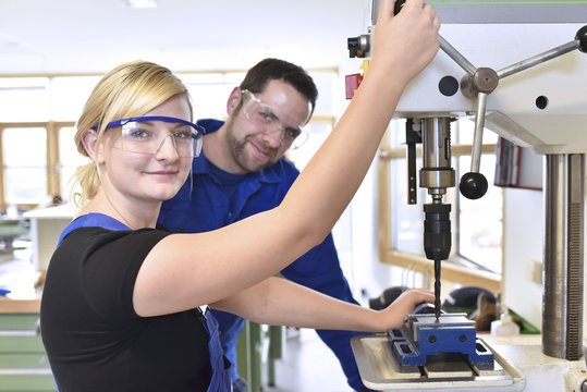Portrait of smiling instructor with female trainee at drill machine
