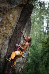 Fototapeta na wymiar Extreme sport climbing. Young male rock climber on a rock wall.