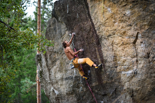 Outdoor sport. Rock climber dangles in midair as he struggles to climb a challenging cliff.