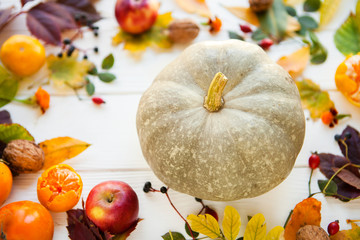 pumpkin and apples and color autumn leaves on a white wooden bac