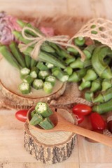 Fresh okra pods and sliced on wood background.