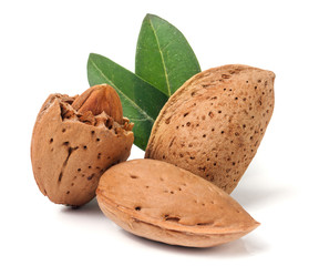 almonds in their skins and peeled with leaf isolated on white background