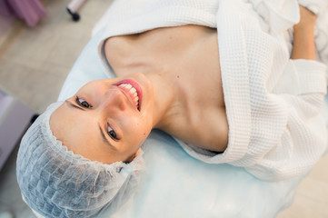 Fototapeta na wymiar Top view of beautiful young woman getting ready for face skin treatment, lying on bed at hospital or clinic