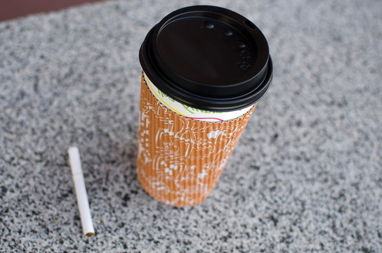Cigarette next to plastic cup