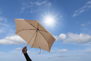 Hand are holding umbrella with blue sky and sunlight background. © ETAP